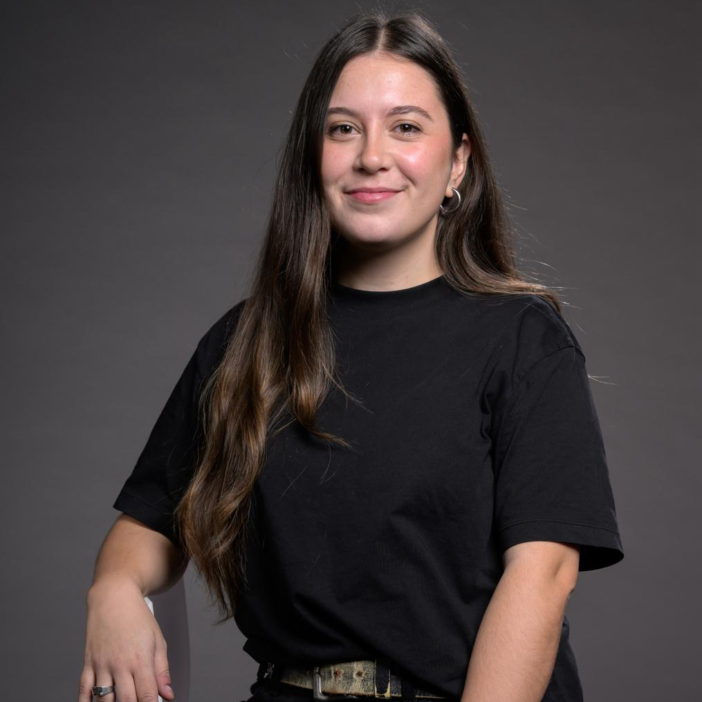 Smiling professional recruiter posing for a headshot in a clean, black outfit in front of a gray background