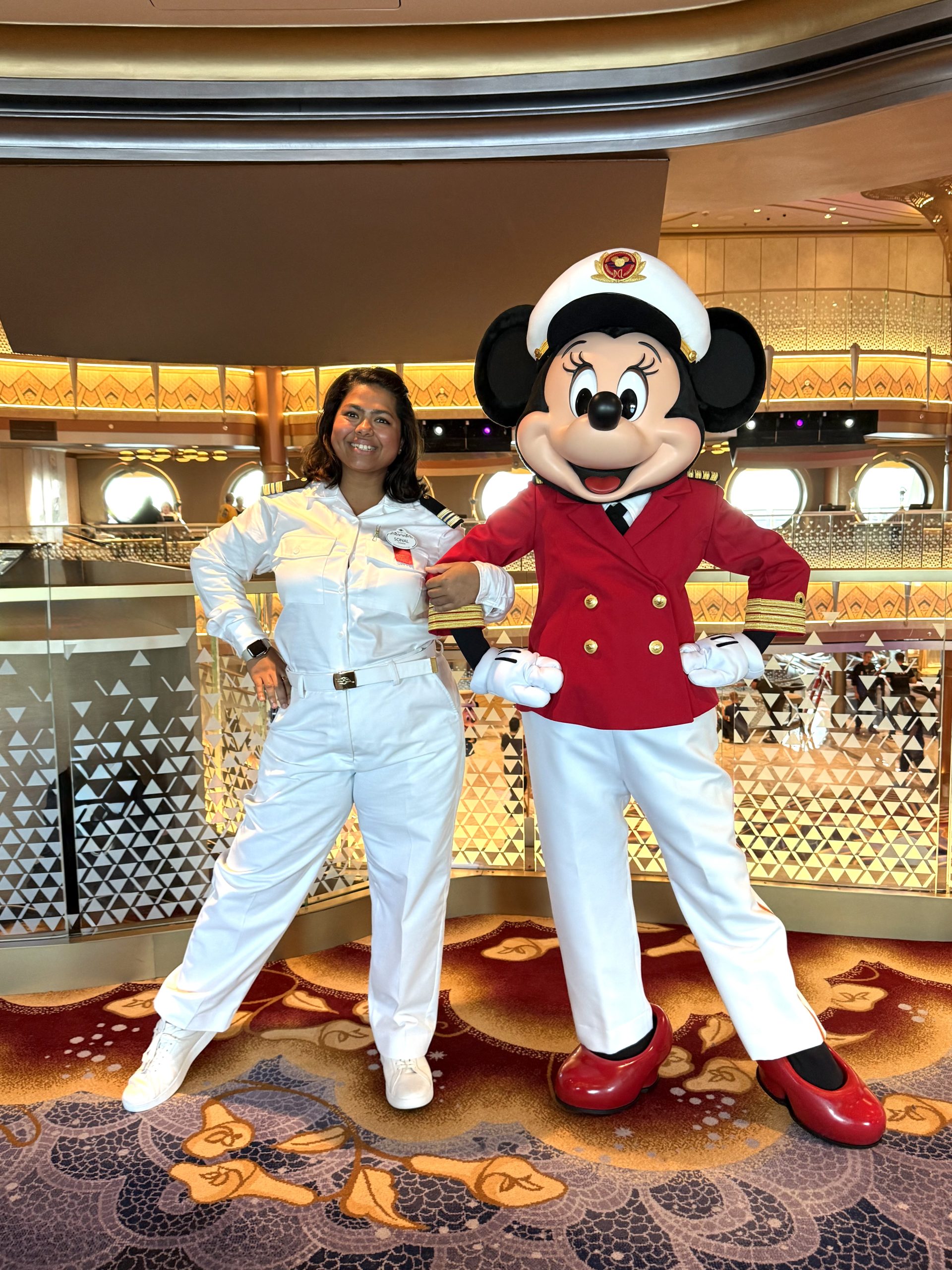 Sonal, Human Resources Manager at Disney Cruise Line, poses with Captain Minnie aboard the Disney Destiny while celebrating shipboard culture and crew experiences.