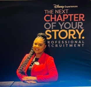 Smiling professional recruiter in a red shirt in front of a recruitment backdrop