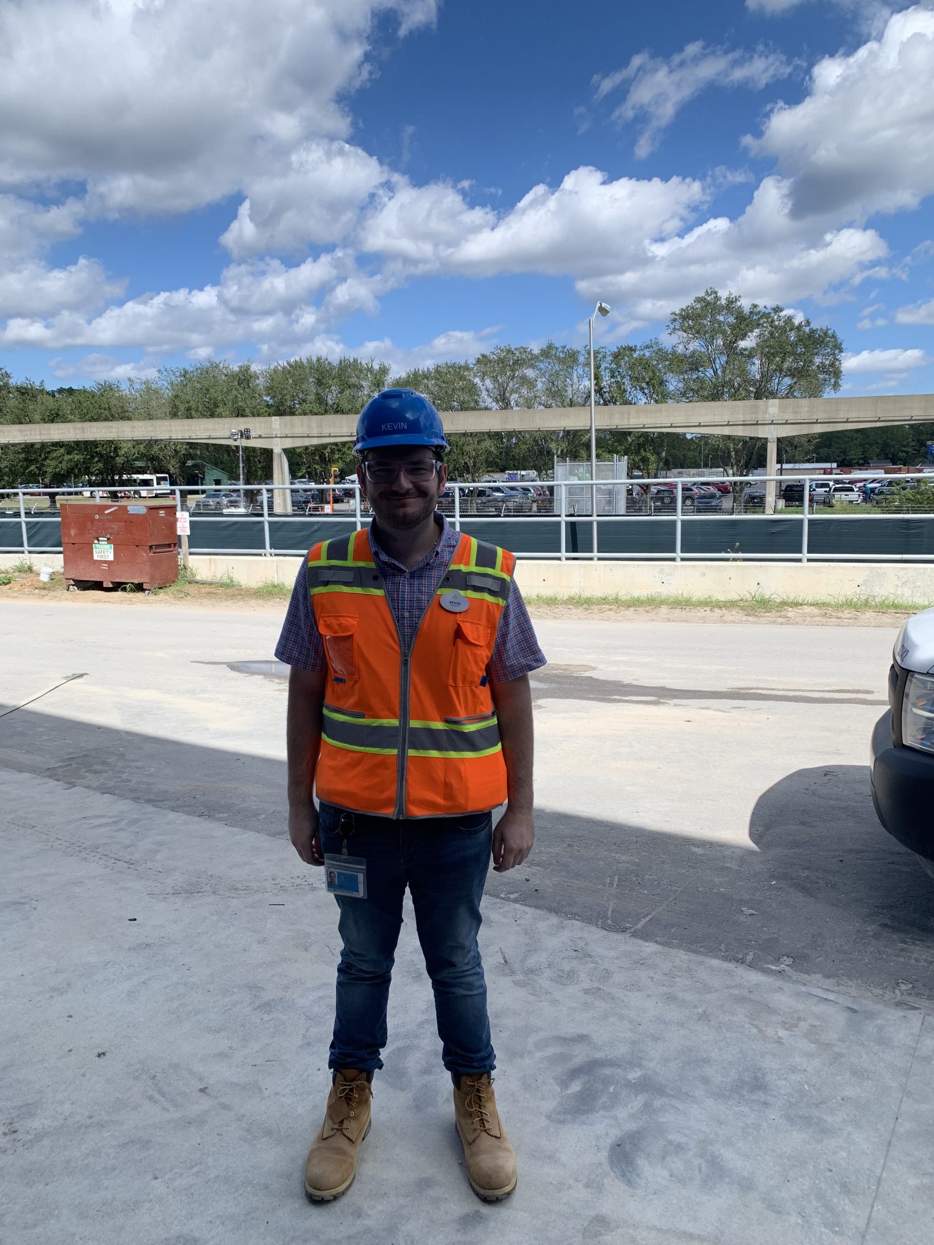 Kevin smiling standing in an orange vest and blue hard hat.