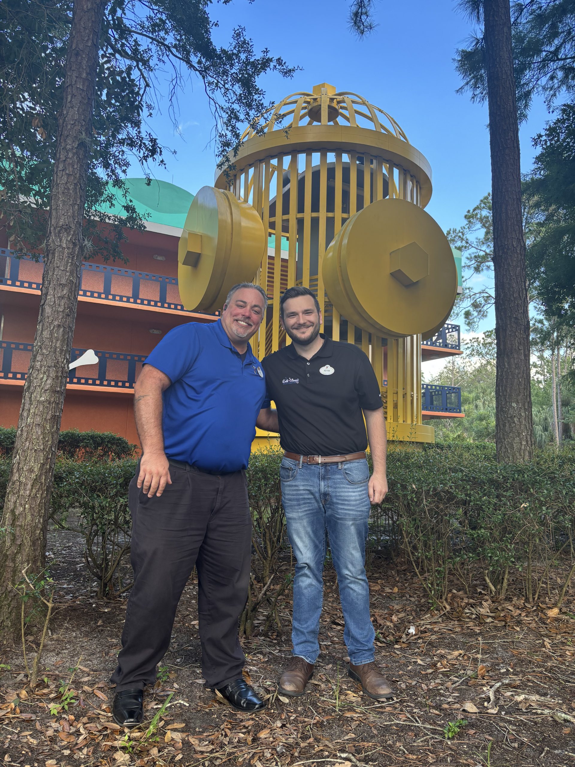 Kevin and Jay smiling in front of large yellow fire hydrant.