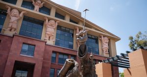 A statue of a Mickey Mouse hand holding a wand in front of The Walt Disney Company building
