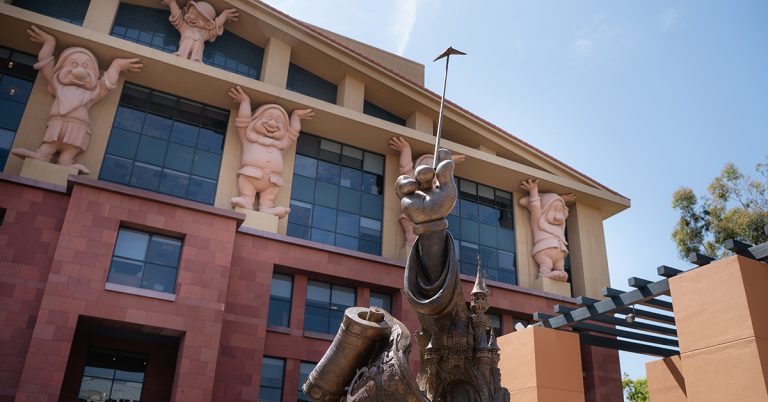A statue of a Mickey Mouse hand holding a wand in front of The Walt Disney Company building