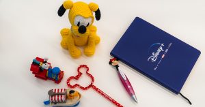 Pluto plush, bentcil, notebook and toys arranged in a flat lay style
