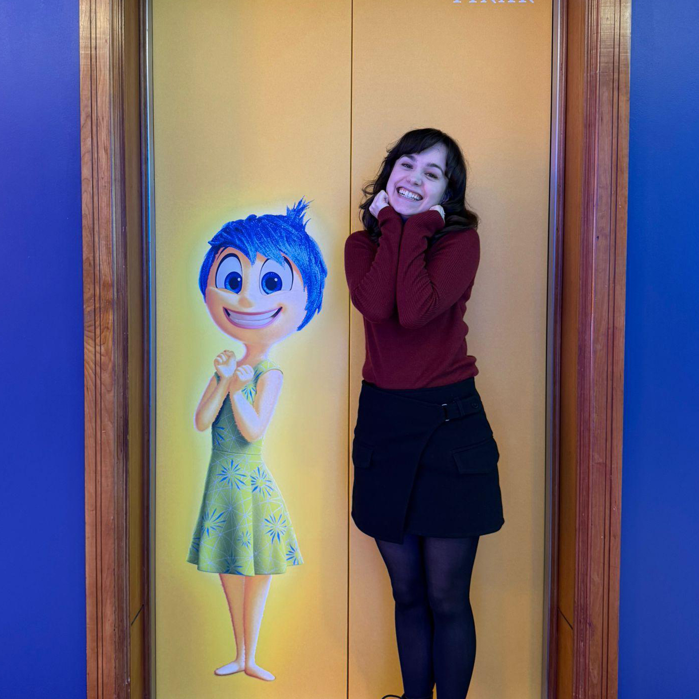 Smiling professional recruiter posing next to a mural of Joy from Pixar's Inside Out