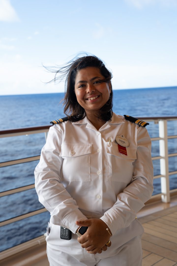 Disney Cruise Line Human Resources Manager Sonal stands onboard with an ocean backdrop, supporting diverse crews and operational excellence at sea.