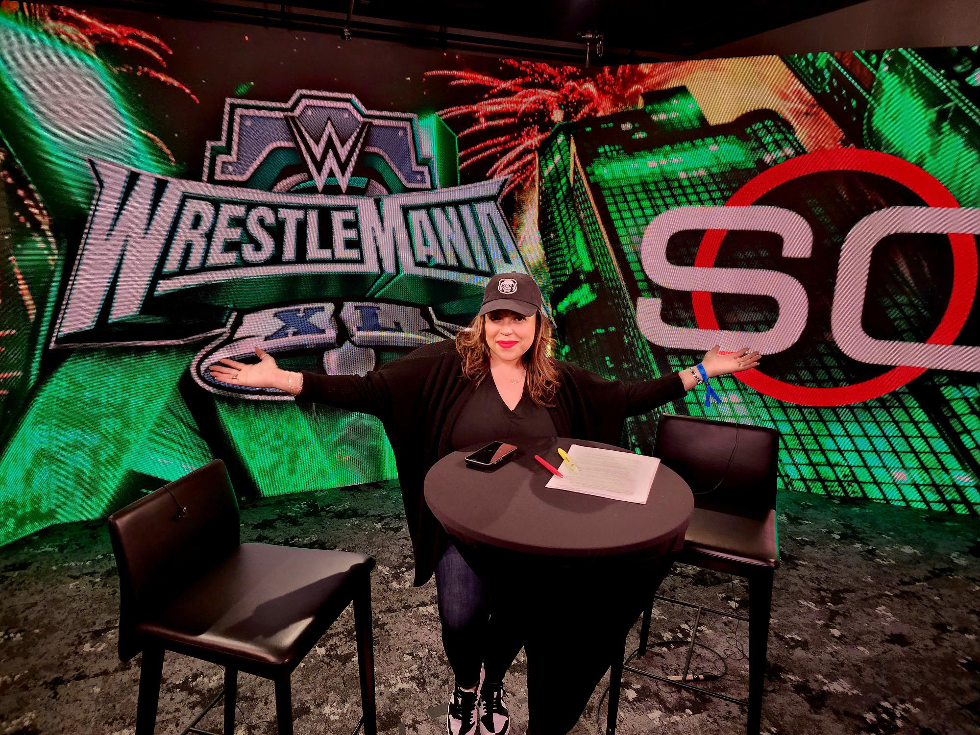 Air, SportsCenter Producer at ESPN, poses on a studio set with prominent SportsCenter and WrestleMania graphics displayed in the background. The image showcases careers in sports journalism, television production, and sports media at Disney and ESPN.