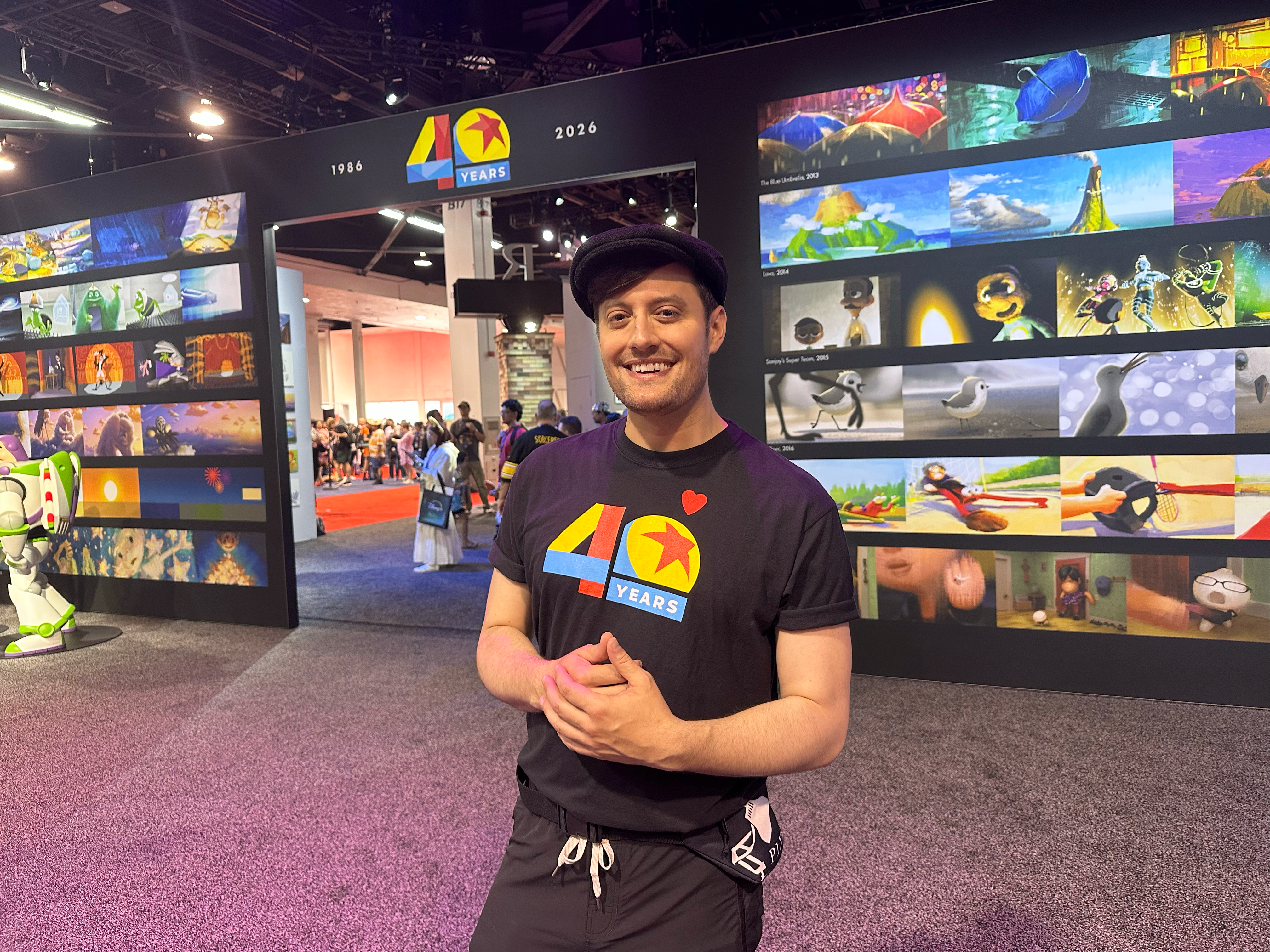 A Pixar Animation Studios employee stands inside Pixar&rsquo;s 40th anniversary exhibit at D23: The Ultimate Disney Fan Event, celebrating the artistry, innovation, and animation careers behind beloved Pixar films and immersive storytelling experiences.