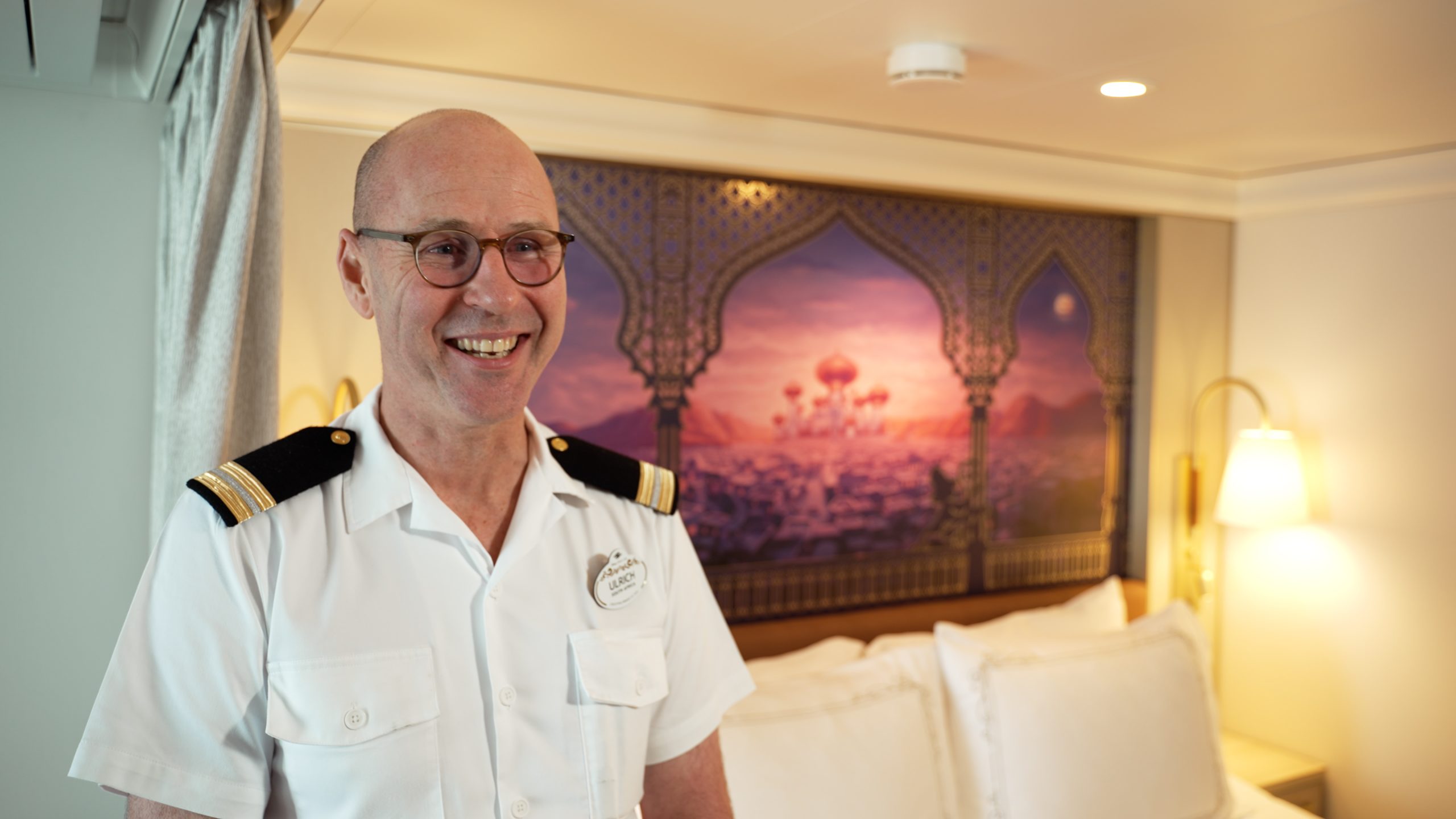 Ulrich, Assistant Housekeeping Manager aboard the Disney Destiny, stands inside a Disney Cruise Line stateroom while discussing safety guidance and training for crew members.