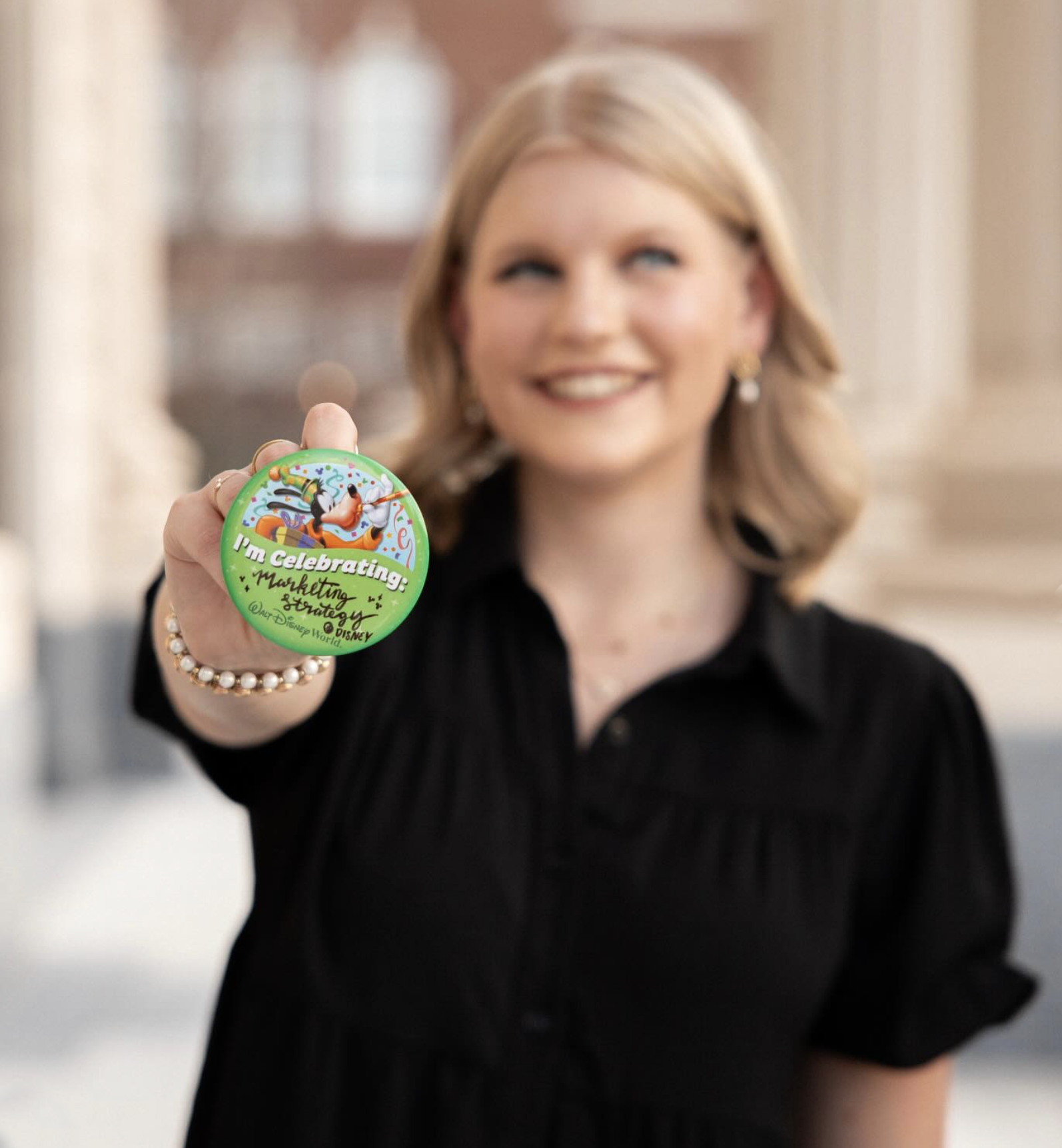 Cast Member Maddie Smiling while holding an "I'm celebrating" Walt Disney World button.