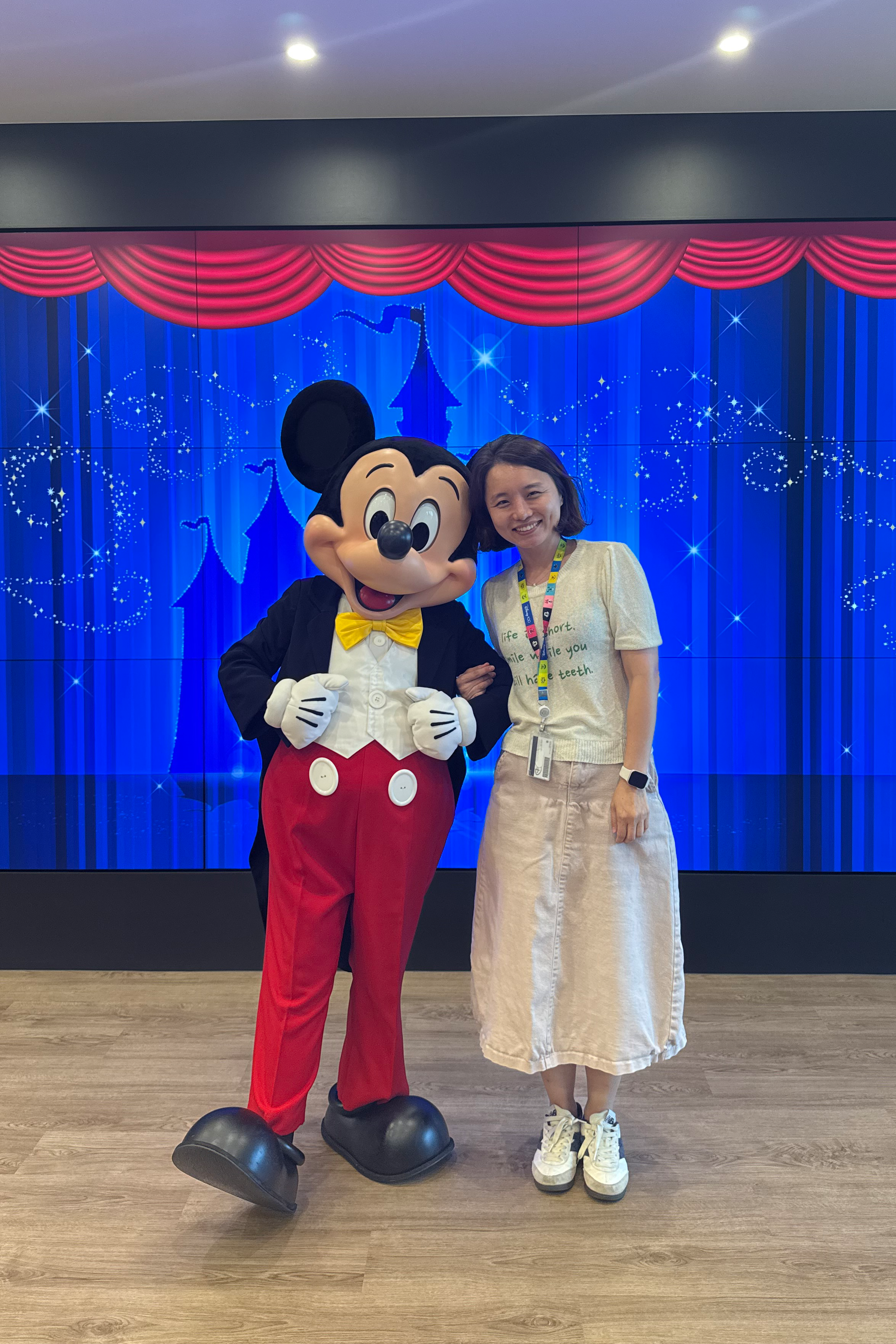 Disney Korea local content employee posing with Mickey Mouse at a Disney event.