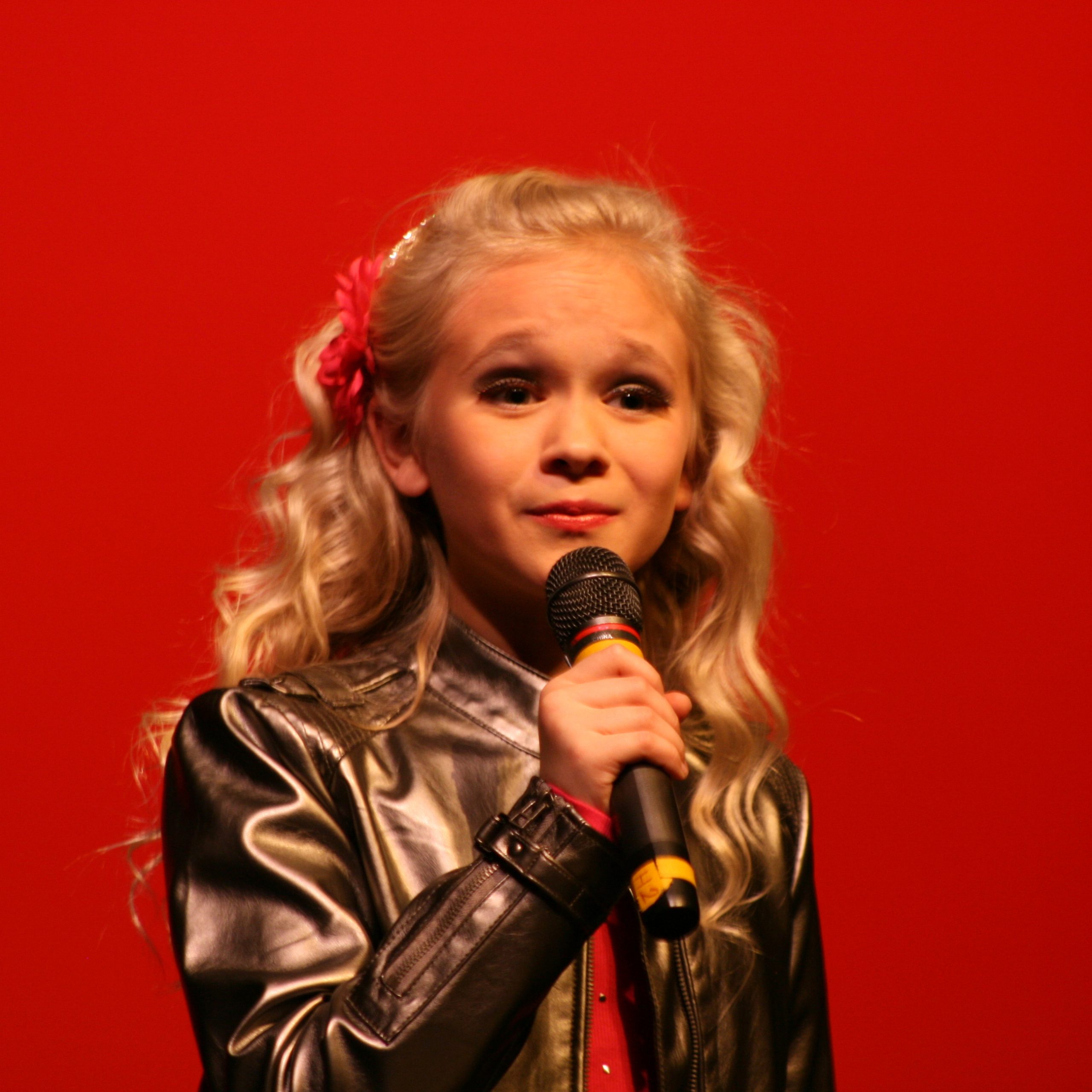 One of the sisters performing onstage with a microphone during a childhood performance.