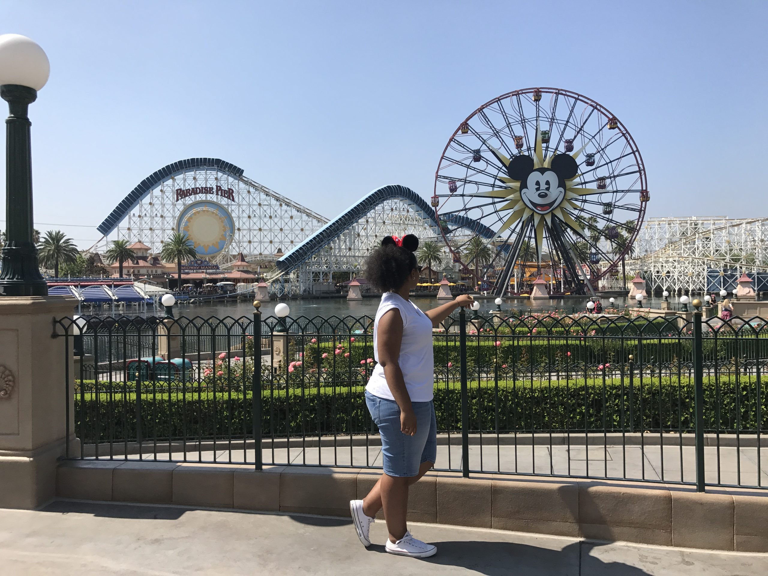 A person stands overlooking Pixar Pier, with the Incredicoaster and Mickey-themed Pixar Pal-A-Round behind them.
