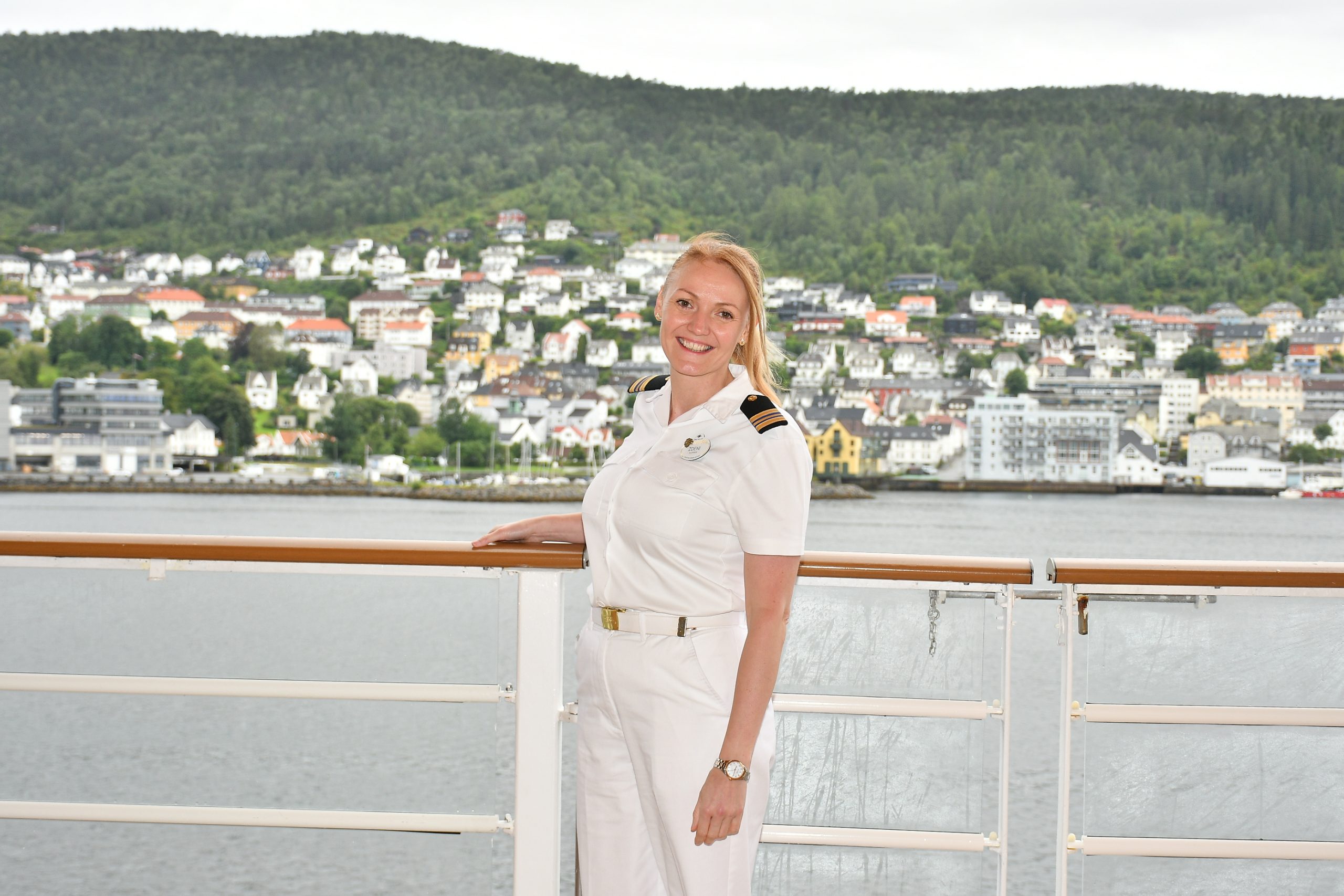 Disney Cruise Line Human Resources Manager Zdeni stands in uniform on a ship deck overlooking a coastal destination.