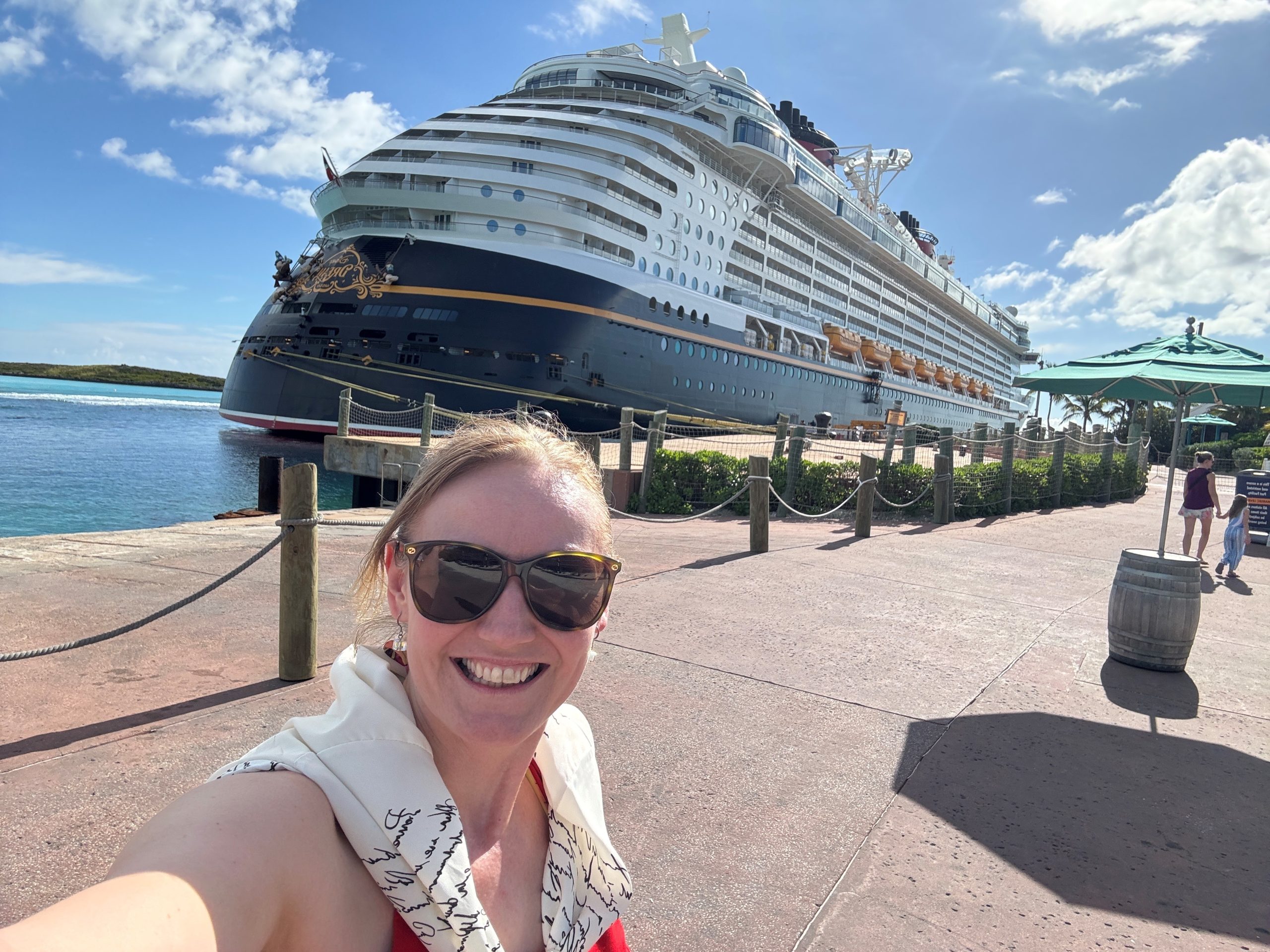 Disney Cruise Line HR professional Zdeni takes a selfie with a Disney cruise ship while docked at a tropical port.