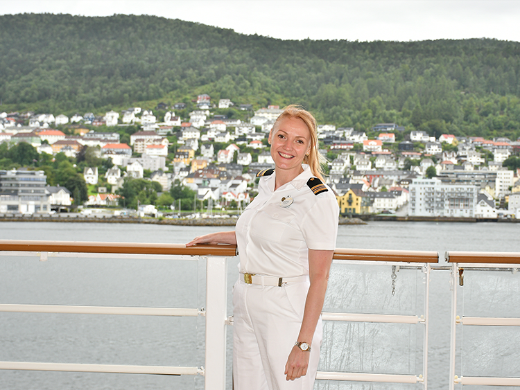Disney Cruise Line Human Resources Manager Zdeni stands in uniform on a ship deck overlooking a coastal destination.