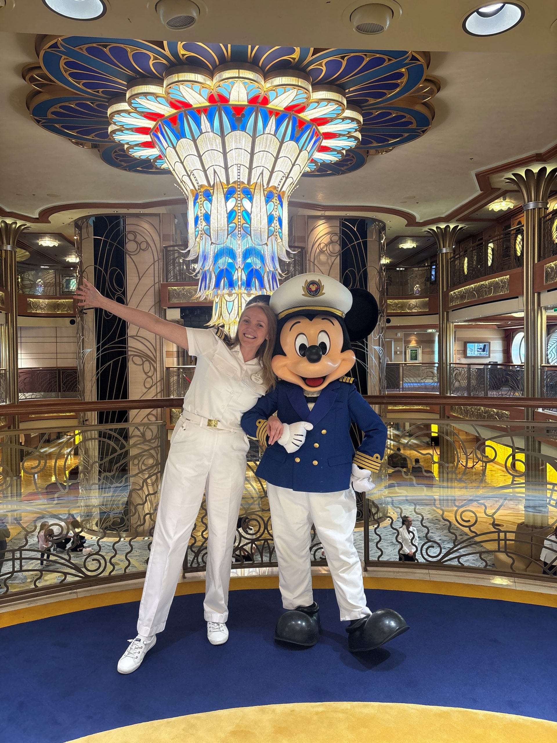Shipboard Human Resources Manager Zdeni poses with Mickey Mouse aboard a Disney Cruise Line ship.