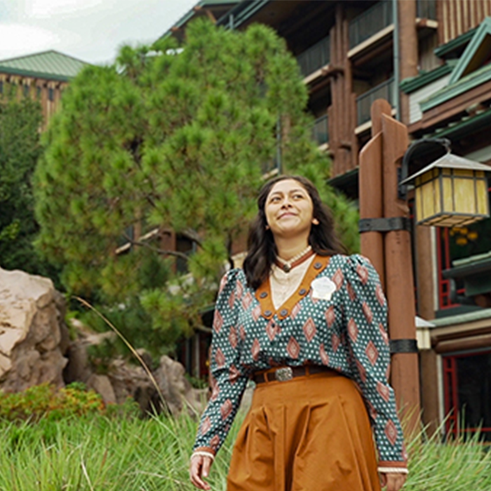 Disney college program female cast member smiling while walking in front of a Walt Disney World Resort