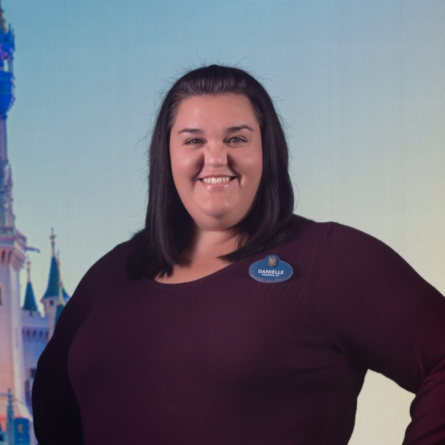 Disney DPEP Tech employee Danielle wearing a burgundy sweater and smiling in front of Cindere;;a's Castle at Walt Disney World