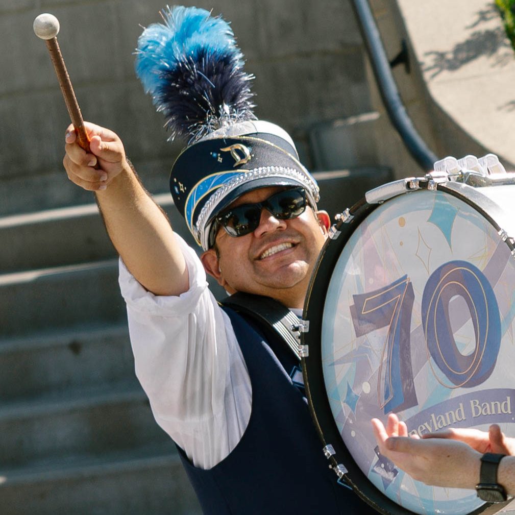 Photo of bass drum player raising his drum stick and smiling