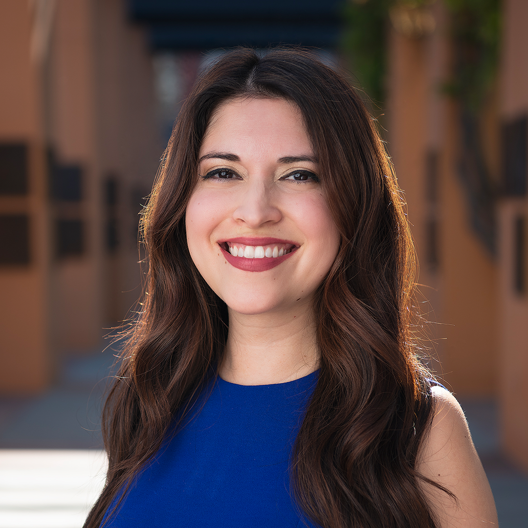 Life at Disney Podcast Season 3 host Lisa, with long brown hair wearing a blue dress