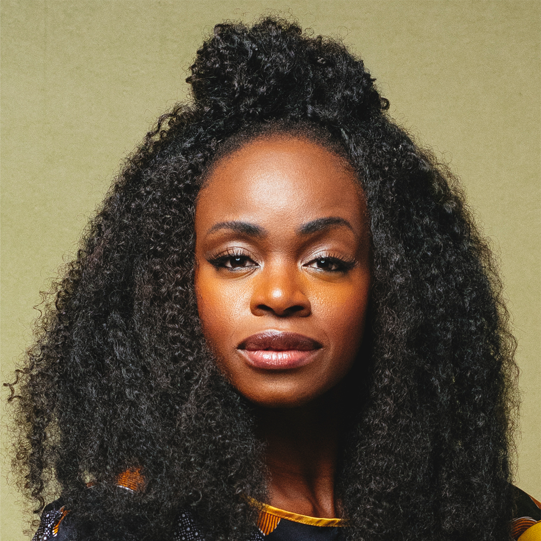 Life at Disney Podcast Season 3 host Nzinga with mid length curly hair wearing a yellow shirt