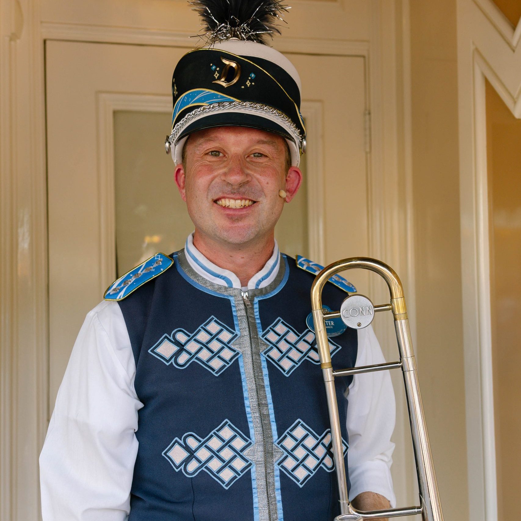 Headshot of trombone player in front of a beige wall