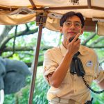 Image of Jungle River Cruise skipper speaking into microphone with elephant animatronic in the background