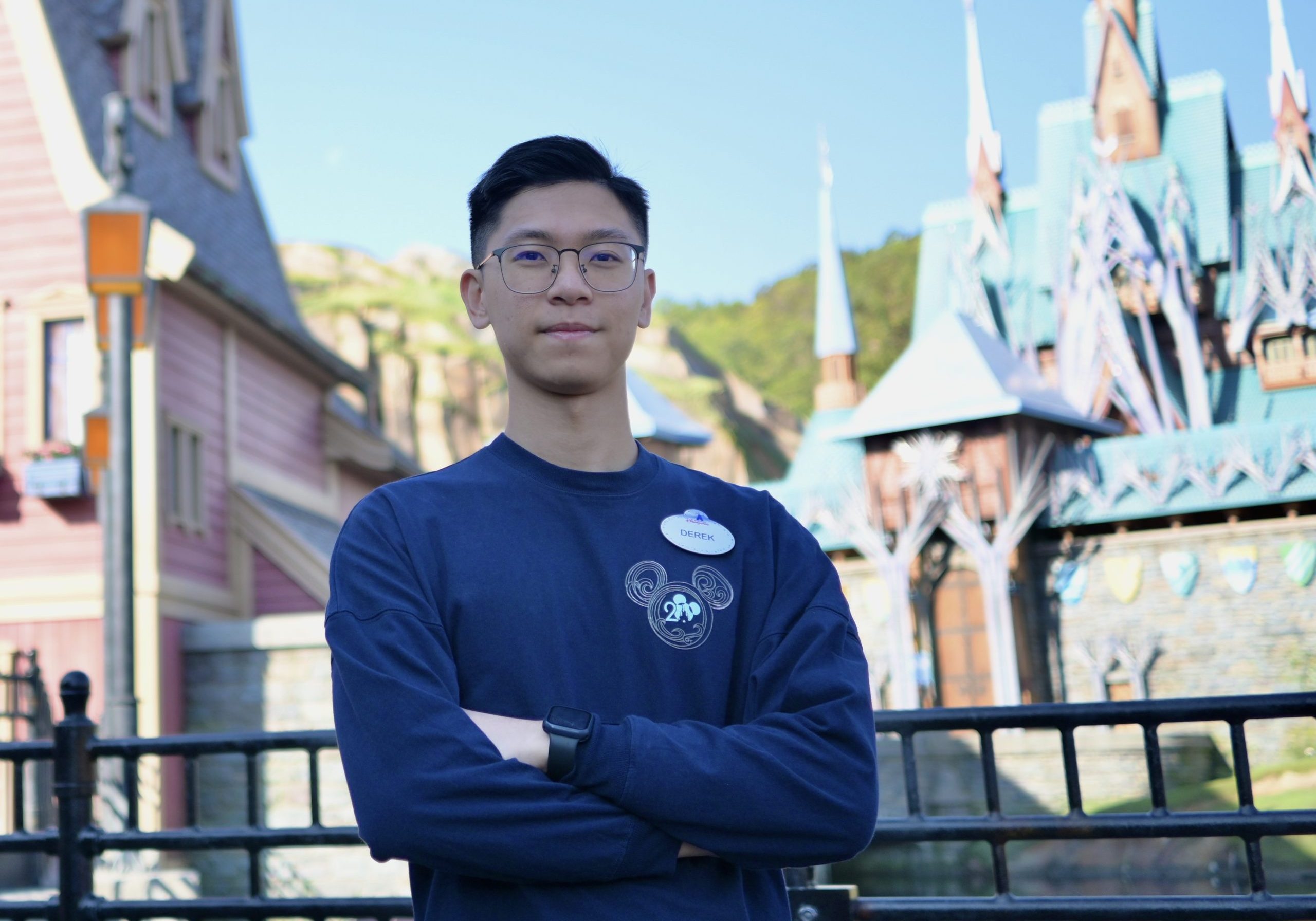 Image of employee with arms crossed in front of World of Frozen at Hong Kong Disneyland