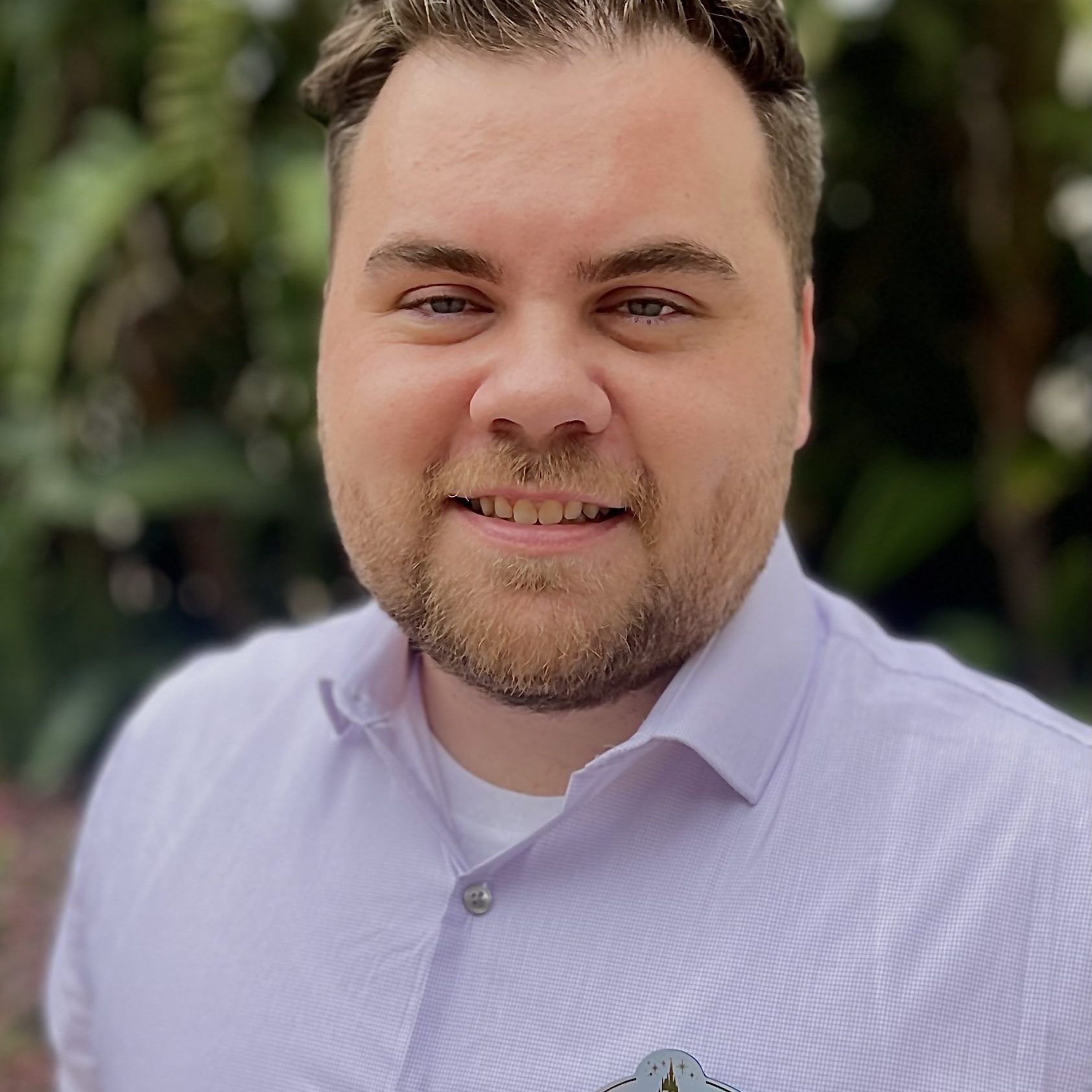 Photo of employee in a light purple shirt in front of a green background