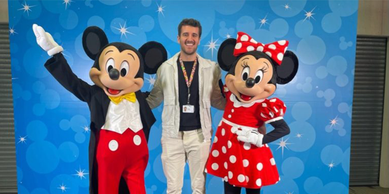 Thiago, participante del Programa LATAM Graduate Trainee, sonríe con Mickey y Minnie Mouse