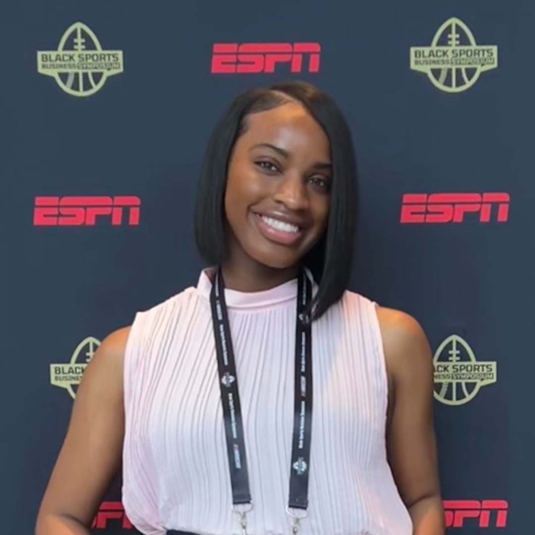 Howard University Alumnus and ESPN production assistant Maya wearing a white blouse and smiling in front of an ESPN event backdrop