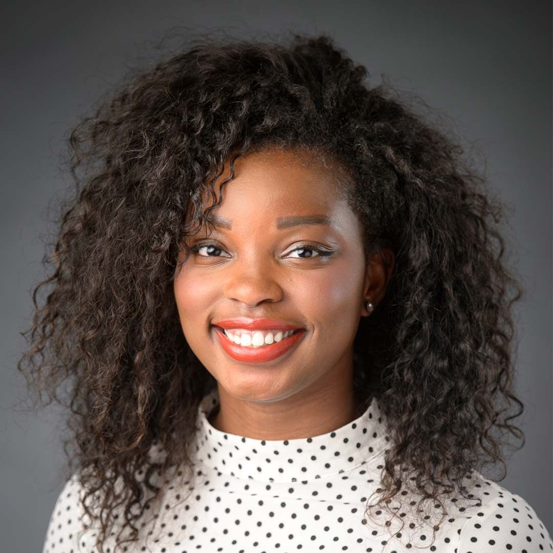 Hampton University alumnus and Disney FX employee Ryan smiling. She is wearing a white and black polka dot blouse and has shoulder-length curly hair.